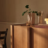 Natural wood tones with warm beige and subtle glass accents, featuring a sleek minimalist design and decorative plants.