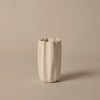 White textured vase with a wavy pattern, featuring unique fluted edges against a beige background.