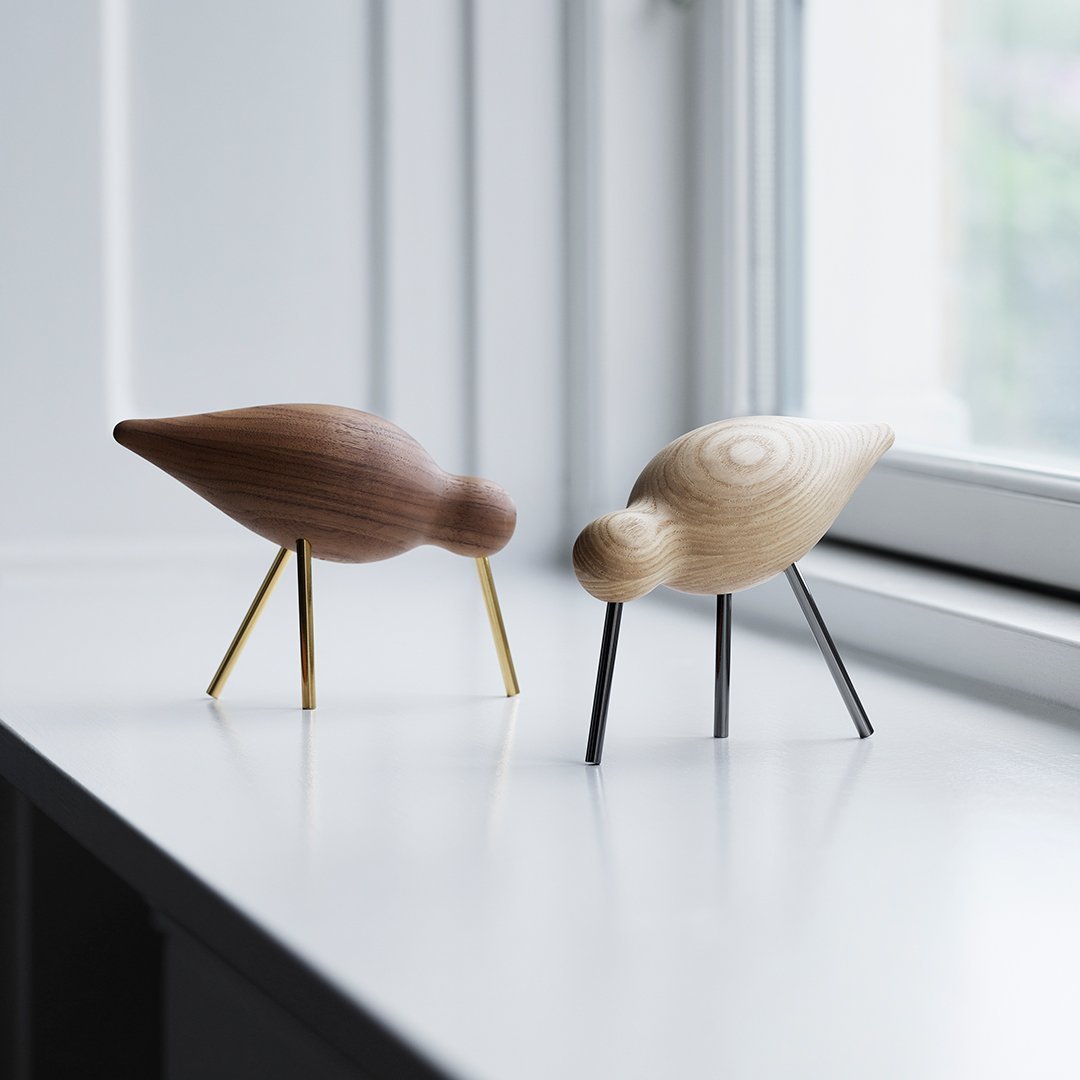 Two wooden bird figurines in light and dark brown with gold and black legs on a white surface.