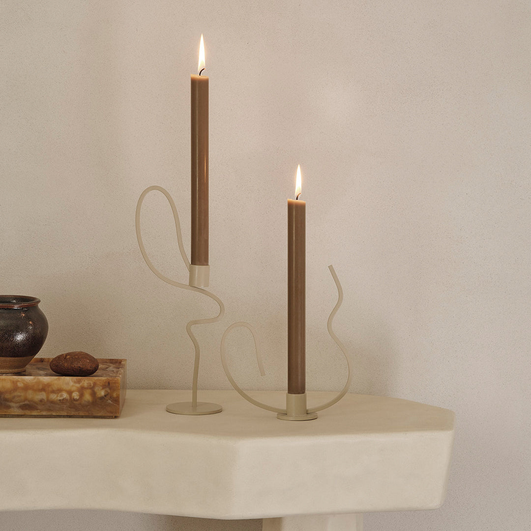 "Modern candle holders in neutral tones with elegant brown candles, featuring abstract, curvy designs."