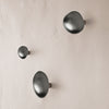 Matte black wall hooks in various sizes against a neutral beige background, showcasing a smooth, modern design.