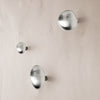 Silver wall hooks with a smooth, shiny finish, featuring three different sizes against a textured light background.