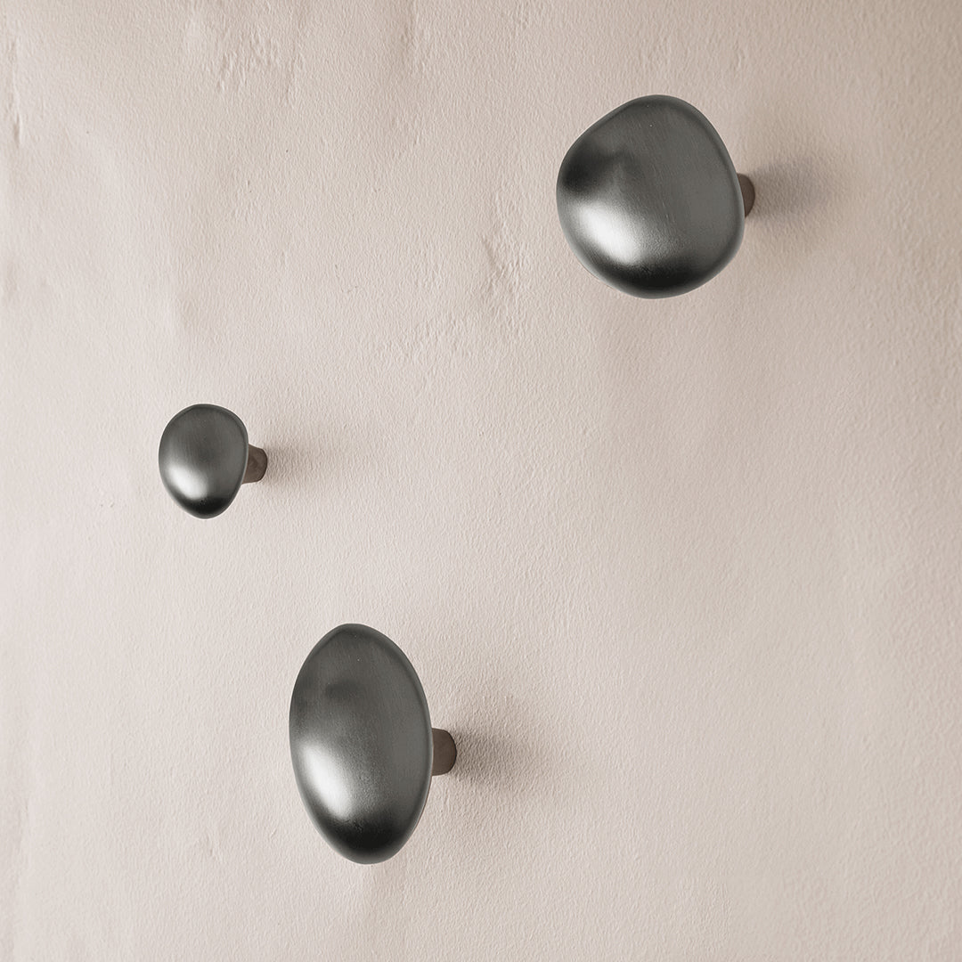 Stylish matte black wall hooks in varied sizes, showcasing sleek, modern shapes against a soft beige background.