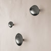 Set of three minimalist black wall hooks on a textured beige background, featuring smooth, rounded shapes.