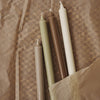 "Set of four tapered candles in earthy tones: olive green, brown, cream, and white on textured brown paper."