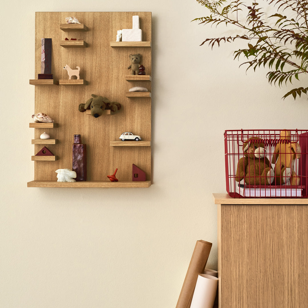 Wooden display shelf showcasing earthy tones, vibrant accents, and playful patterns against a neutral wall.