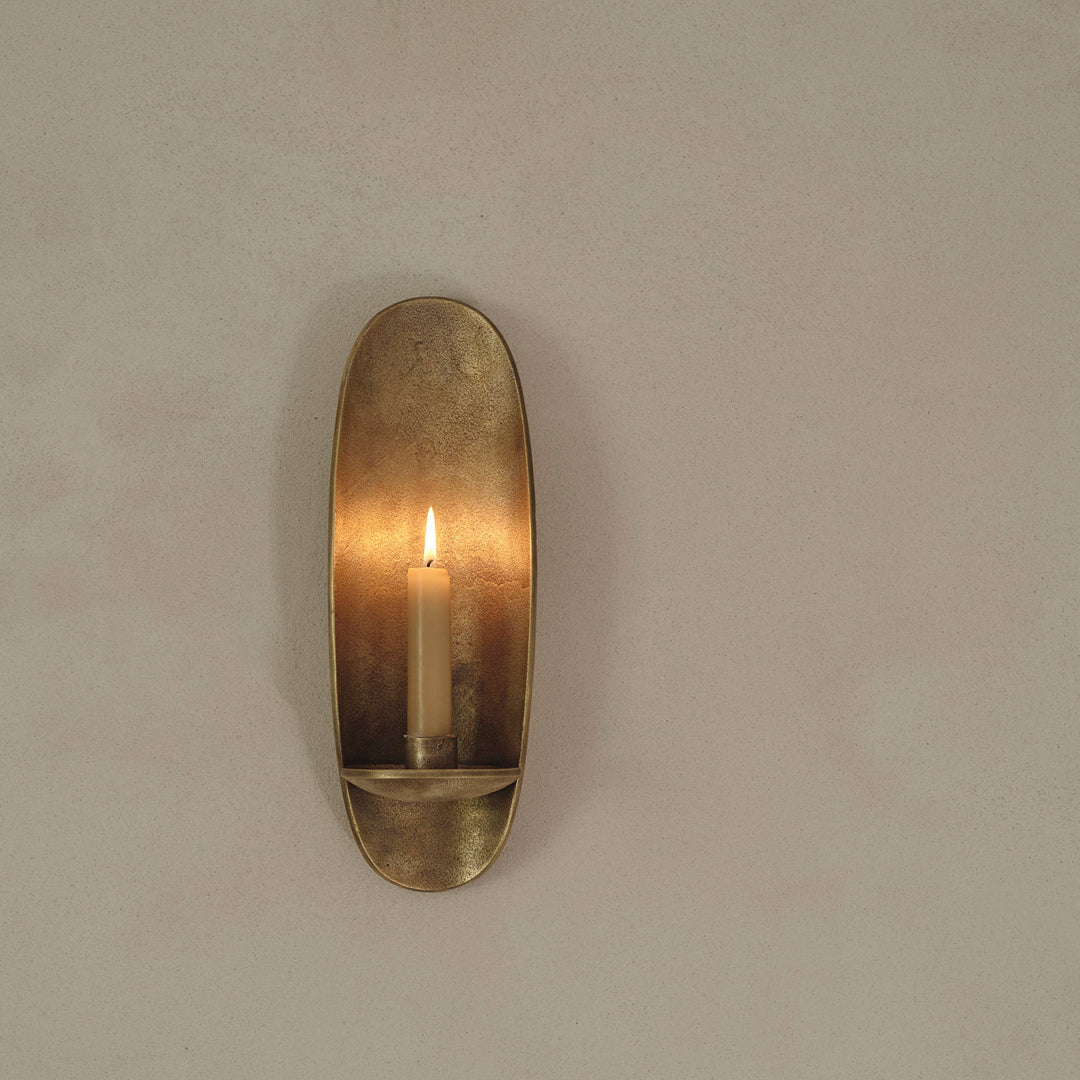 Bronze wall sconce with a sleek oval shape, featuring a warm, glowing candle in a minimalist design.