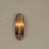 Bronze wall sconce with a sleek oval shape, featuring a warm, glowing candle in a minimalist design.