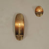 "Elegant brass wall sconces with smooth, reflective surfaces, featuring warm candlelight accents."