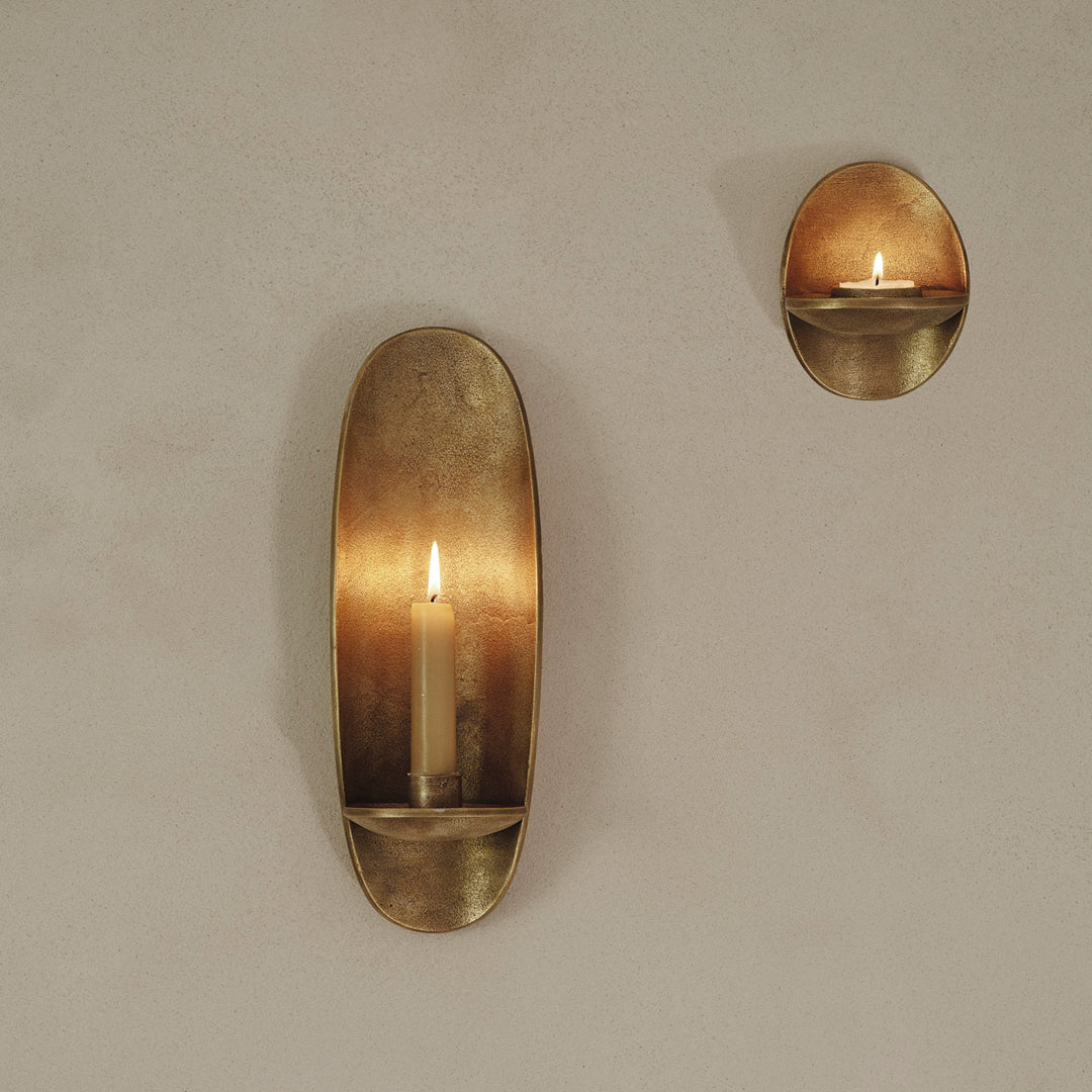 Brushed gold wall sconces featuring smooth, oval designs with warm candlelight glow. Ideal for elegant decor.