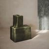 Green abstract-shaped vase with a matte finish, showcasing a unique geometric design against a soft backdrop.