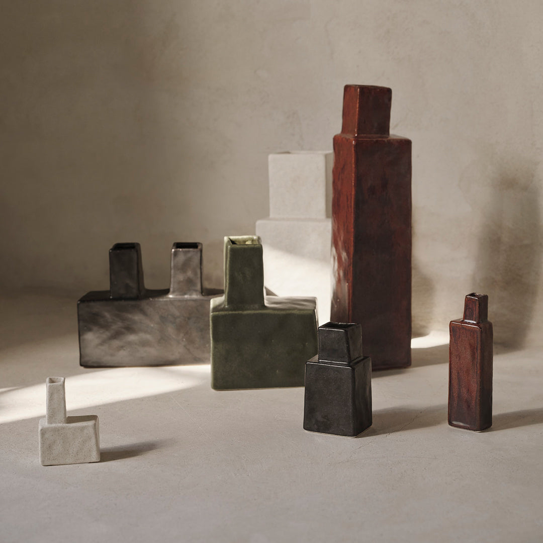 "Artistic vases in gray, green, black, white, and terracotta, featuring unique geometric patterns and textures."