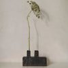 Modern black concrete vase with a sleek design, showcasing a minimalist aesthetic and natural green floral accents.