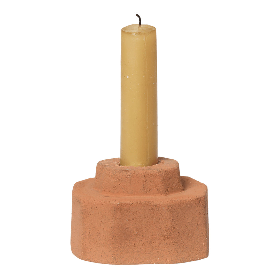 Terra cotta candle holder with a tall yellow candle, featuring minimalistic and earthy design elements.