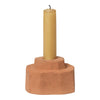 Terra cotta candle holder with a tall yellow candle, featuring minimalistic and earthy design elements.