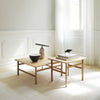 "Light wood coffee tables with a minimalist design, set against a soft neutral backdrop and bright natural lighting."