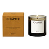 Sleek amber glass candle with a minimalist black and white label, housed in a textured orange box.