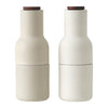 Neutral beige ceramic salt and pepper shakers with smooth textures and natural wooden tops.