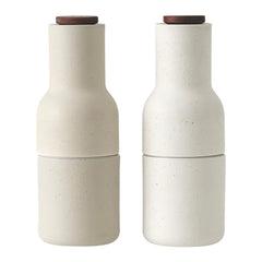 Neutral beige ceramic salt and pepper shakers with smooth textures and natural wooden tops.