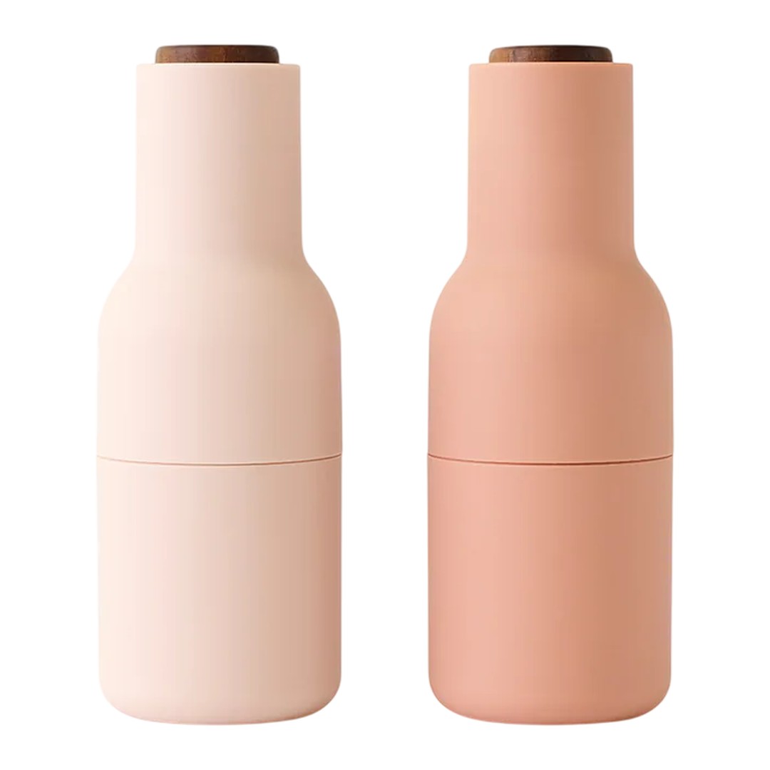 Pink and soft peach double-layered bottles with sleek matte finish and wooden lids.