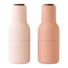 Pink and soft peach double-layered bottles with sleek matte finish and wooden lids.