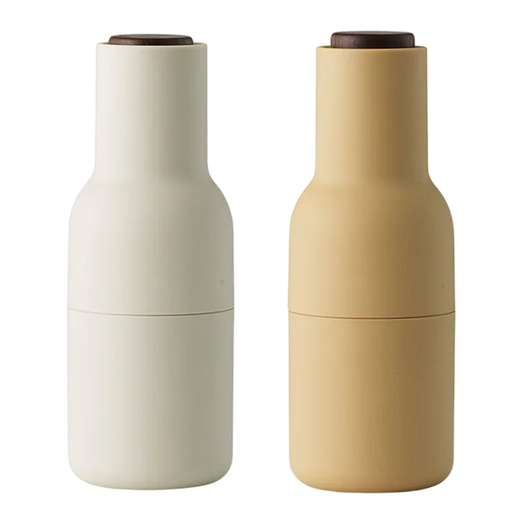 Pair of minimalist bottle-shaped containers in matte white and soft beige with brown lids.
