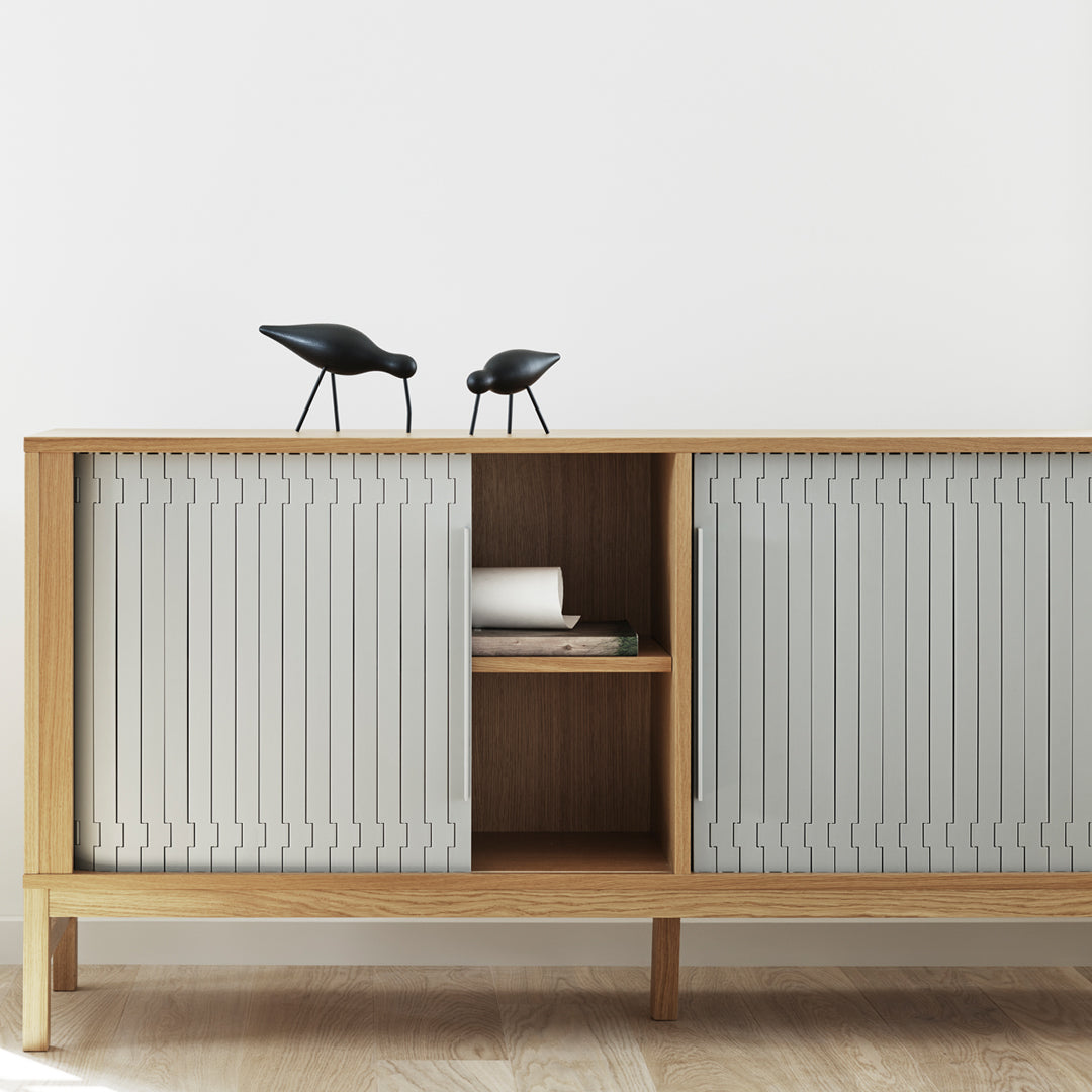 Light grey paneling with a ridged pattern on a wooden cabinet, complemented by black decorative birds.
