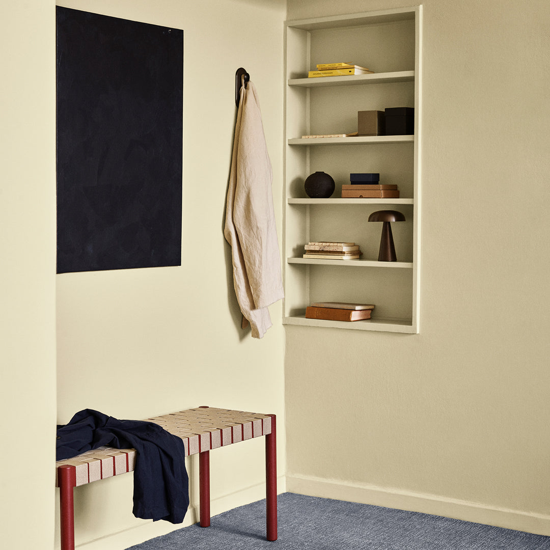 Cream-colored walls with navy artwork, striped red and beige bench, and blue carpet. Stylish and modern decor elements.