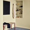 Cream-colored walls with navy artwork, striped red and beige bench, and blue carpet. Stylish and modern decor elements.