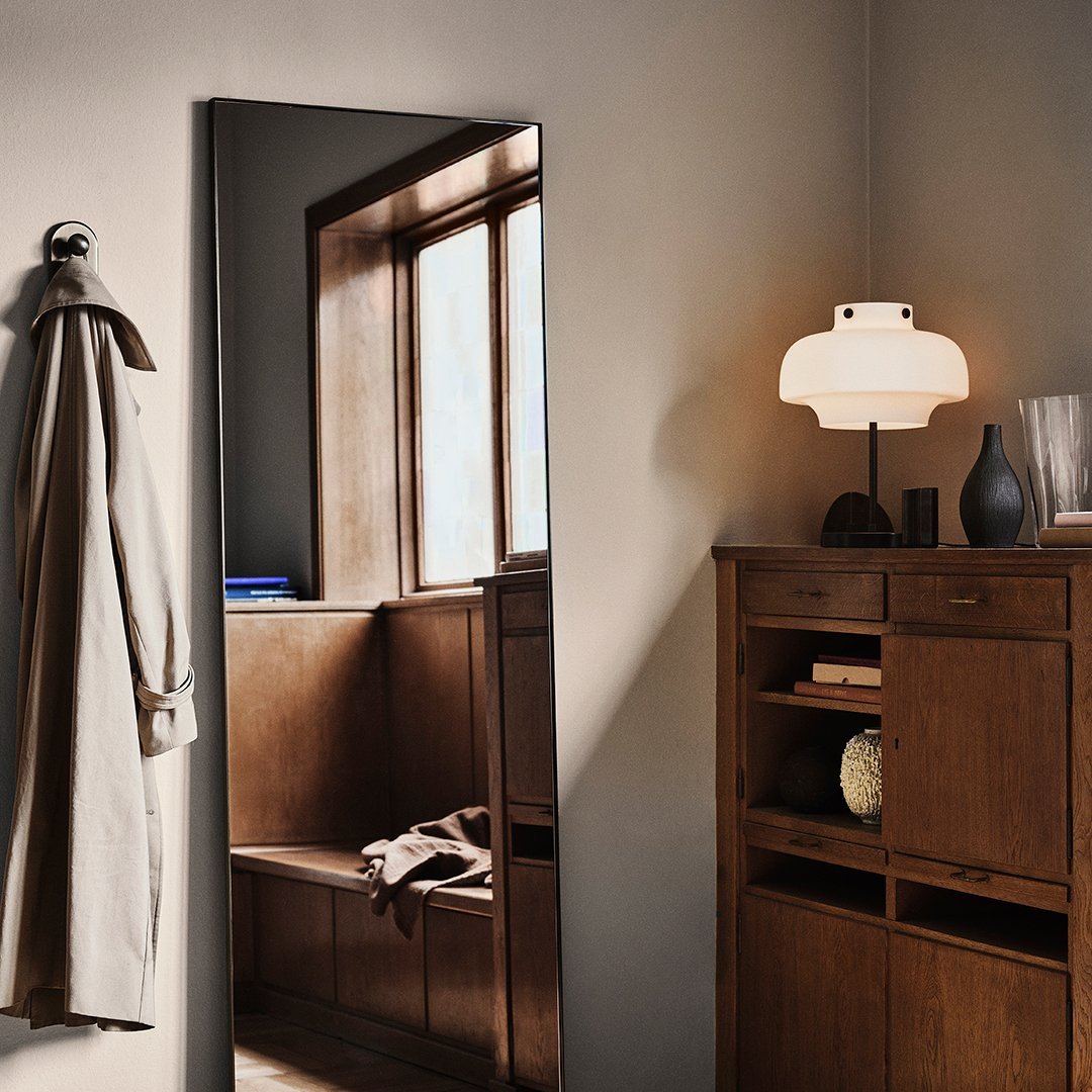 "Minimalist mirror in a warm-toned room with neutral décor, soft lamp, and wooden furniture accents."