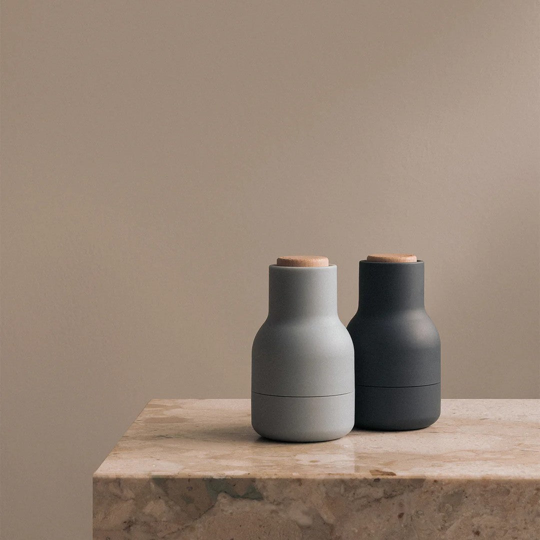 Two modern vases in soft gray and deep charcoal with wooden accents, styled on a light stone surface.
