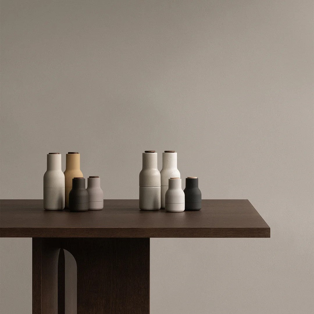 Set of textured ceramic vases in beige, gray, white, and black, displayed on a wooden table against a neutral wall.