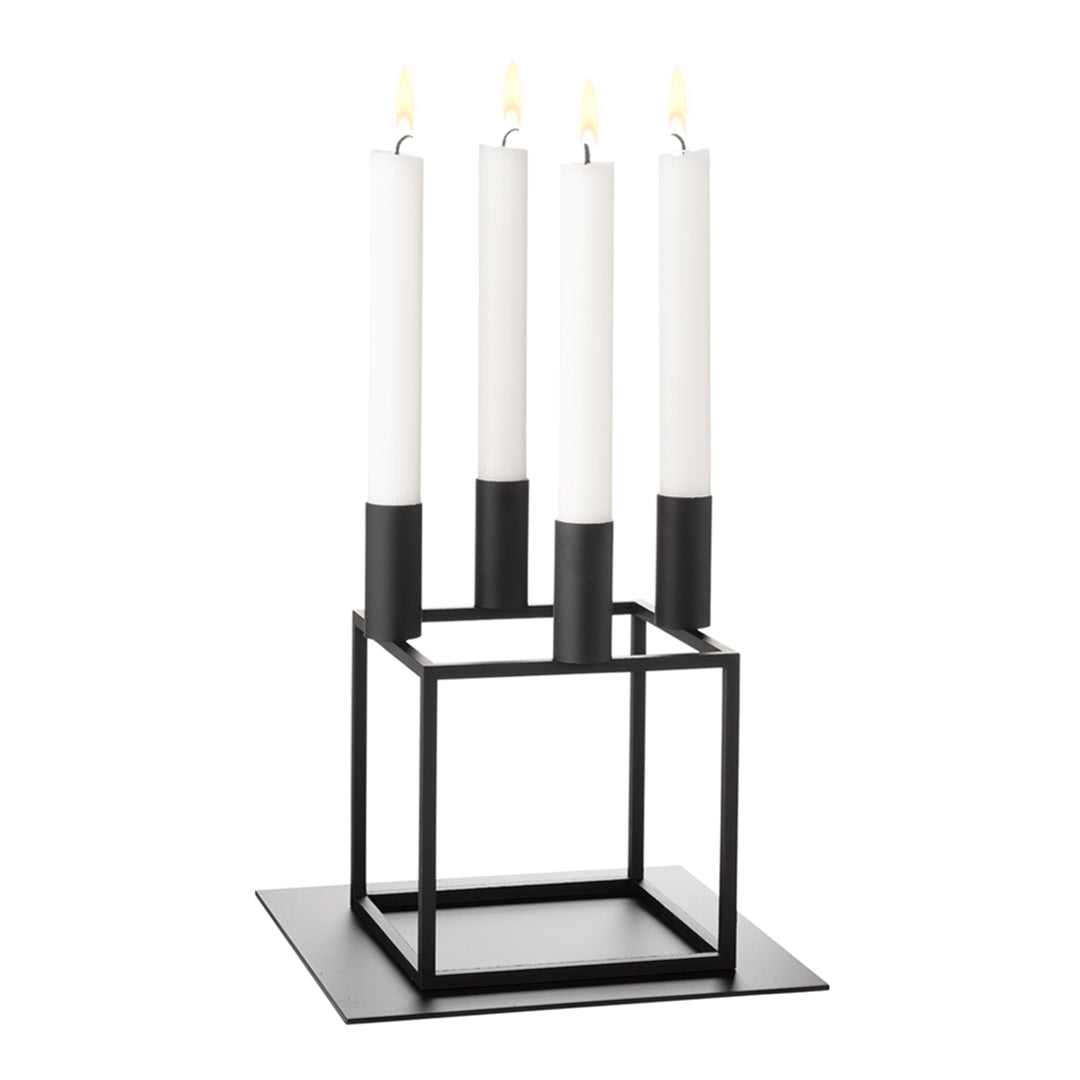 Minimalist black candle holder with four white candles and sleek geometric design. Perfect for modern decor.