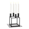 Minimalist black candle holder with four white candles and sleek geometric design. Perfect for modern decor.