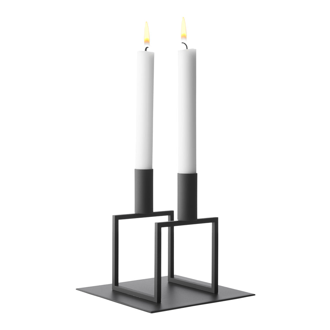 Minimalist black candle holder with two white candles, featuring modern geometric design and clean lines.