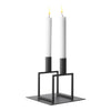 Minimalist black candle holder with two white candles, featuring modern geometric design and clean lines.