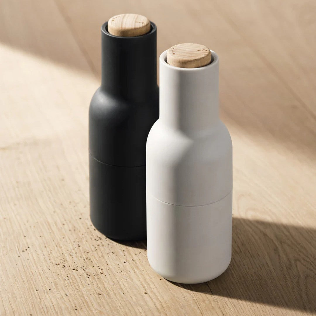 Black and white ceramic bottles with wooden corks against a light wood background.