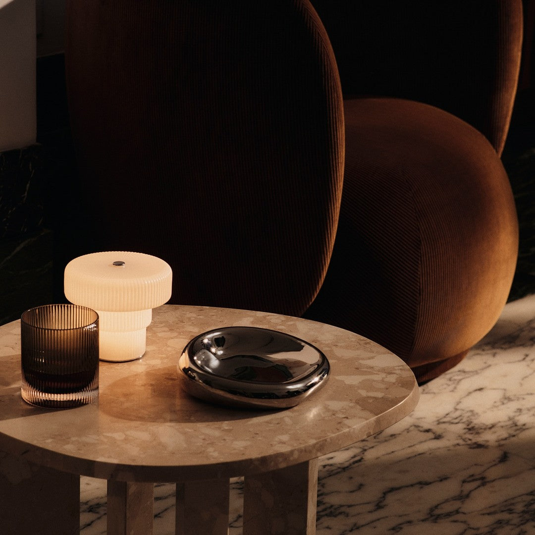 Modern decor featuring warm brown, soft cream, smoky grey, and sleek metallic accents on a marble tabletop.