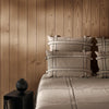 Beige bedding set featuring black grid patterns on pillows and quilt against a warm wooden backdrop.