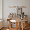 Modern wooden dining set with light tones, featuring a gray pendant light and white decorative accents. 