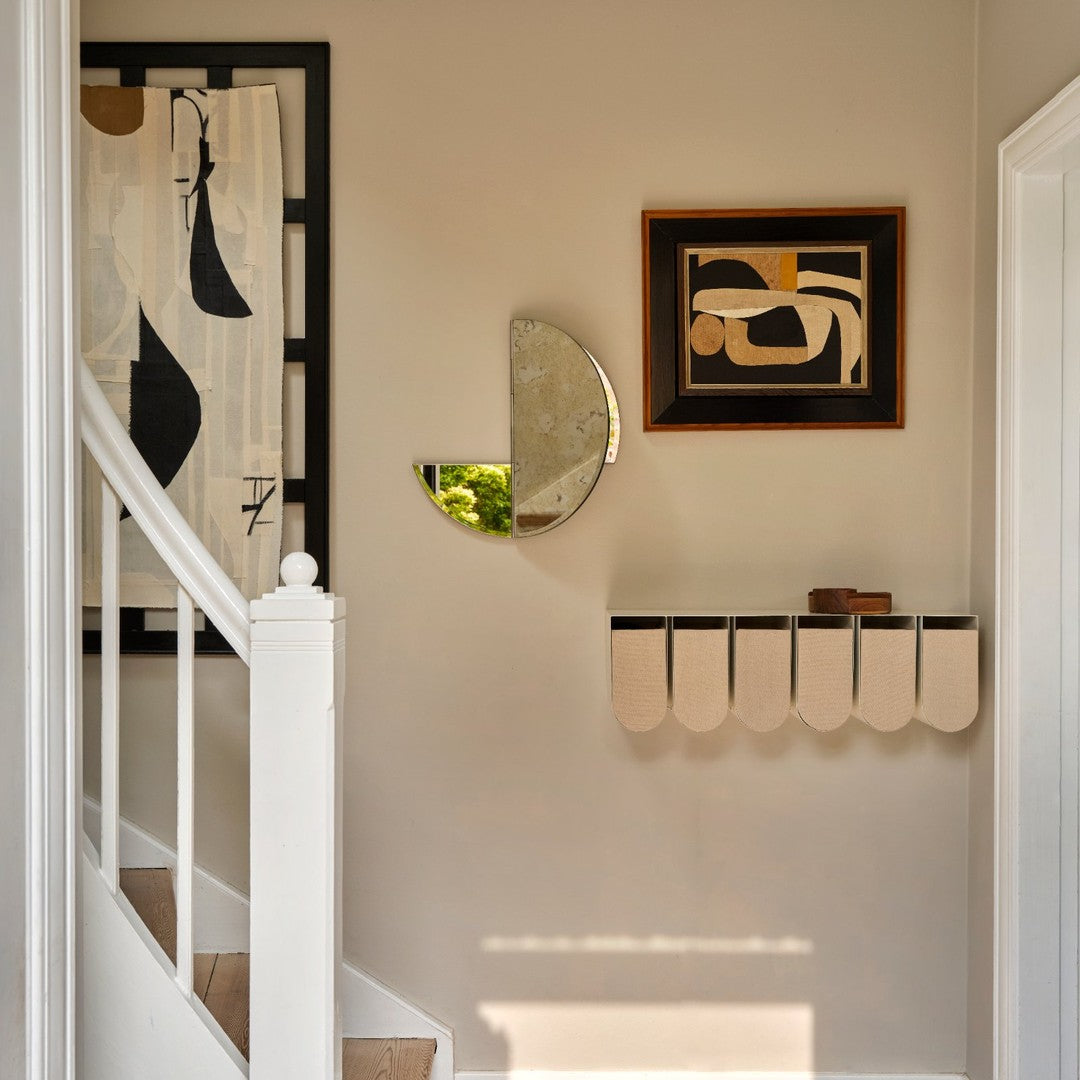 Abstract geometric patterns in neutral tones with a mix of black, cream, and gold accents in a modern hallway.