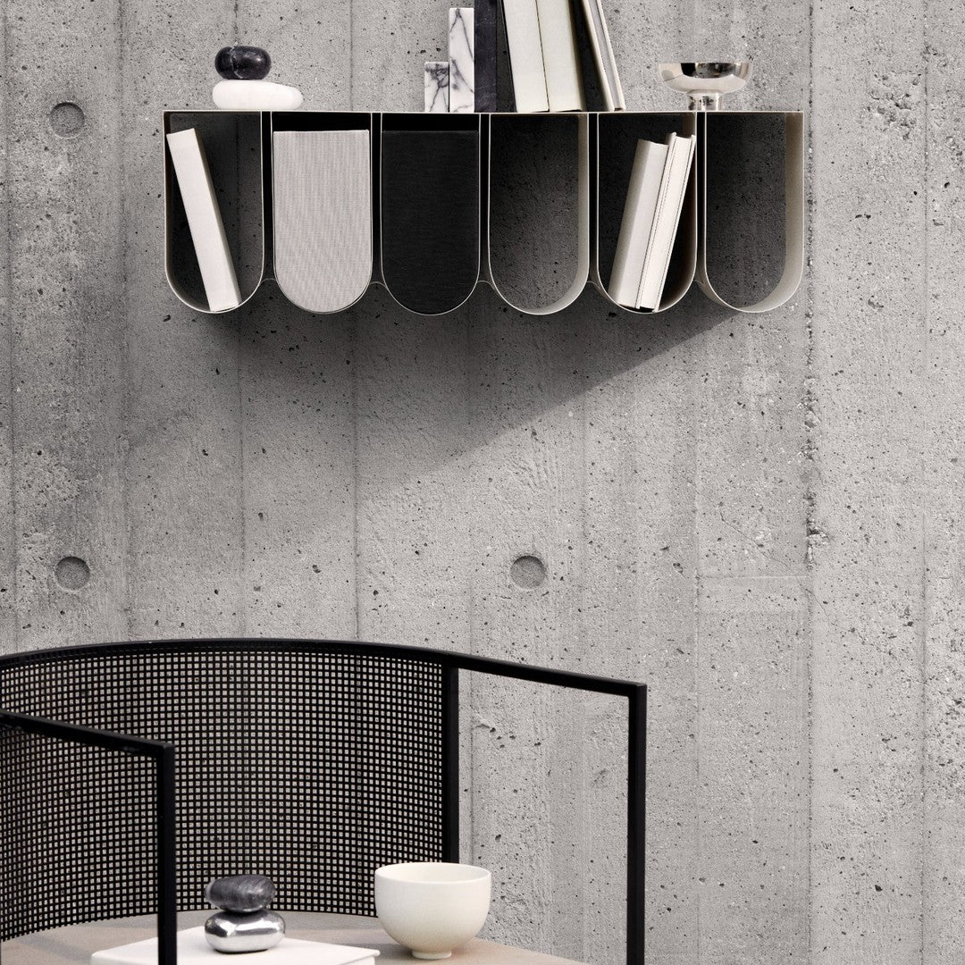 Modern black and white bookshelf with curved shelves, set against a textured gray concrete wall.