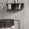 Modern black and white bookshelf with curved shelves, set against a textured gray concrete wall.