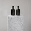 Two sleek black vases on a white marble pedestal, showcasing a modern, minimalistic design.