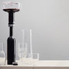 Black wine decanter with clear glassware on a light wood surface and soft grey background. Elegant and modern design.