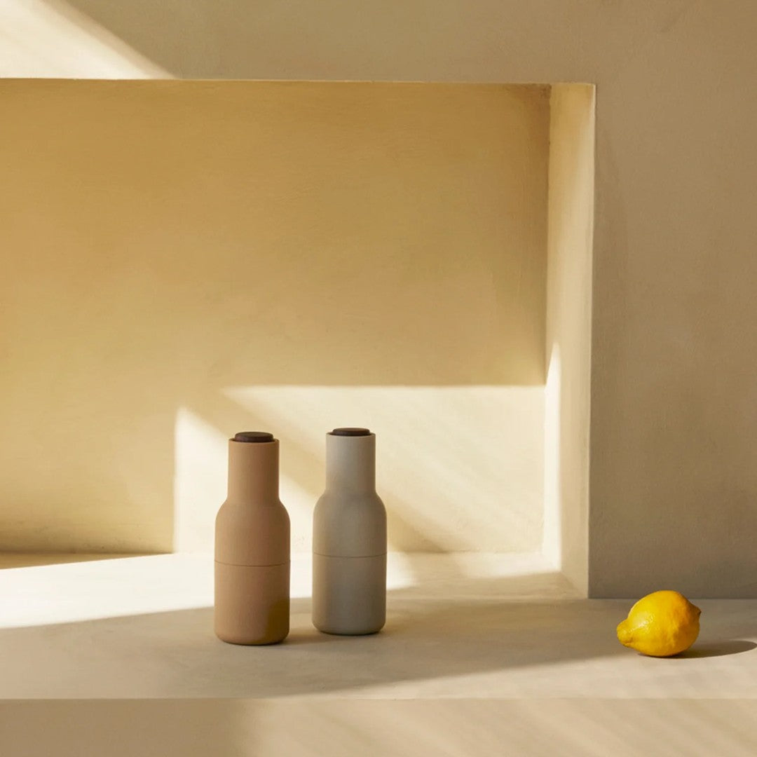 Two matte vases in soft beige and gray, featuring a minimalist design, against a warm, neutral background.
