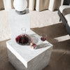 "Modern marble side table with a sleek white finish, showcasing subtle gray veining, contrasted by dark glassware."