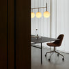 Modern office interior featuring a sleek black table, brown chair, and round white pendant lights against white curtains.