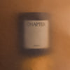 Blurry candle with a black label, set against warm amber tones and soft gradients.