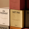 Colorful candle packaging featuring soft pink, golden, beige, and earthy tones with bold black text.